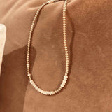 Gold wrap bracelet with pearls that doubles as a necklace on a rust velvet background