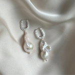 Large Baroque Pearl earrings with silver hooks on a beige fabric background