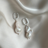 Large Baroque Pearl earrings with silver hooks on a beige fabric background