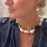 Close-up of a person wearing a pearl necklace and earrings.