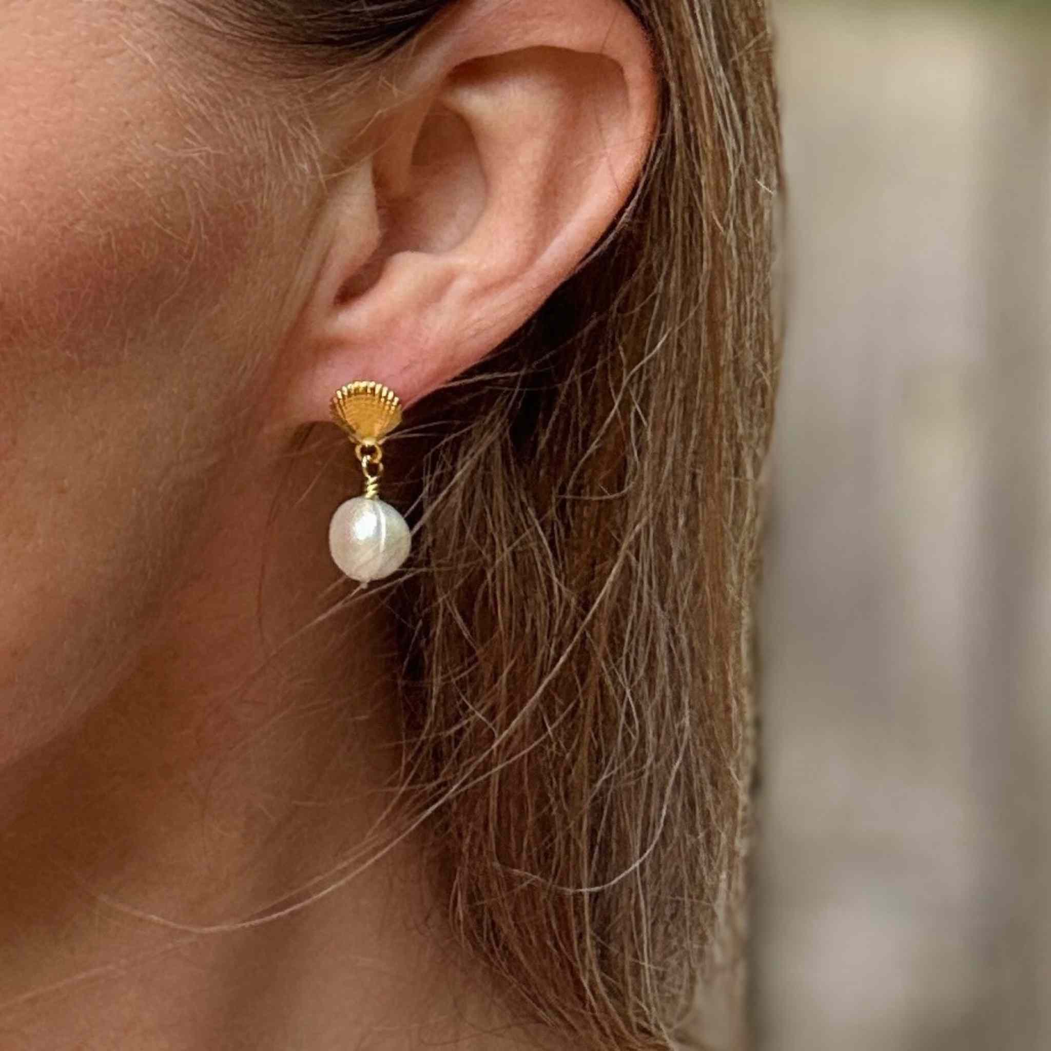 Sea shell earrings with pearls modelled against long dark blond hair