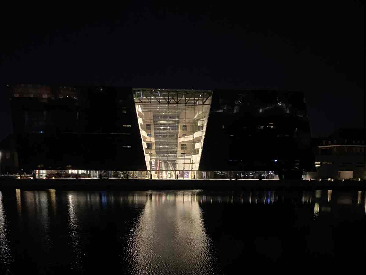 Image of the Black Diamond in Copenhagen taken at night time, the black diamond is the modern annex of the royal library in Copenhagen, at night the light form within this modern piece of architecture is reflected in the waters of Copenhagen Harbour