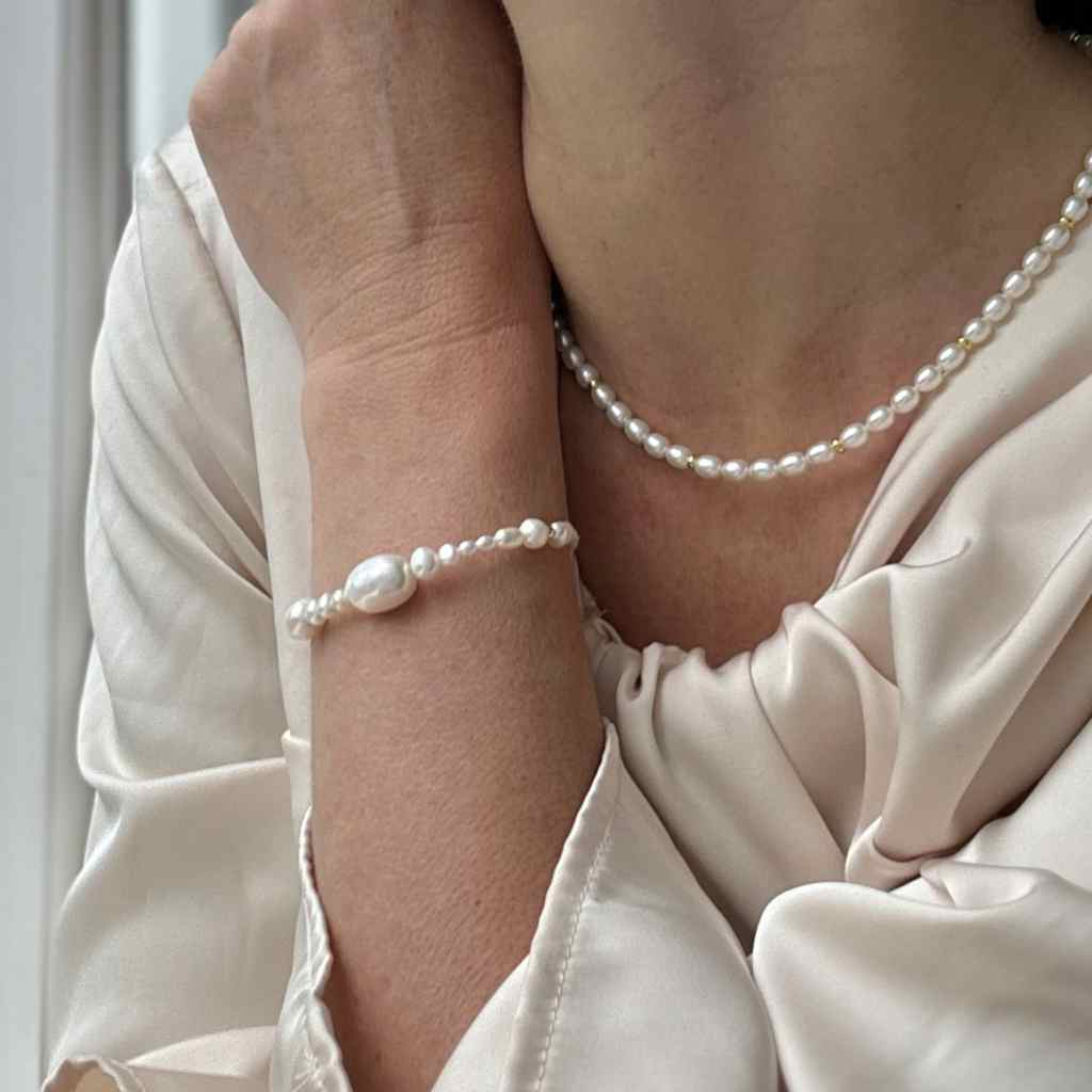 Modern classic pearl design for you as a bride and a bridesmaid. image show woman in off white silk wedding dress and a pearl bracelet and elegant choker necklace in pearls