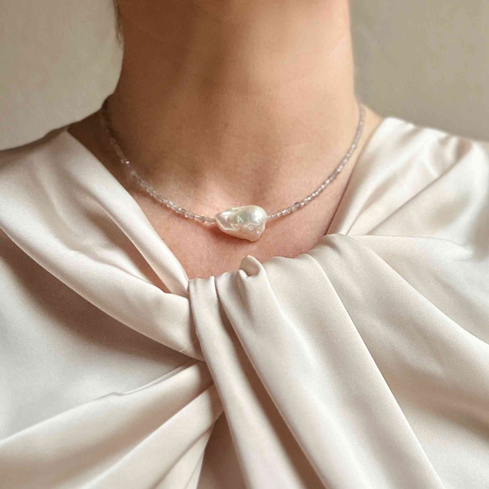 Baroque pearl and labradorite choker modelled against a cream silk blouse