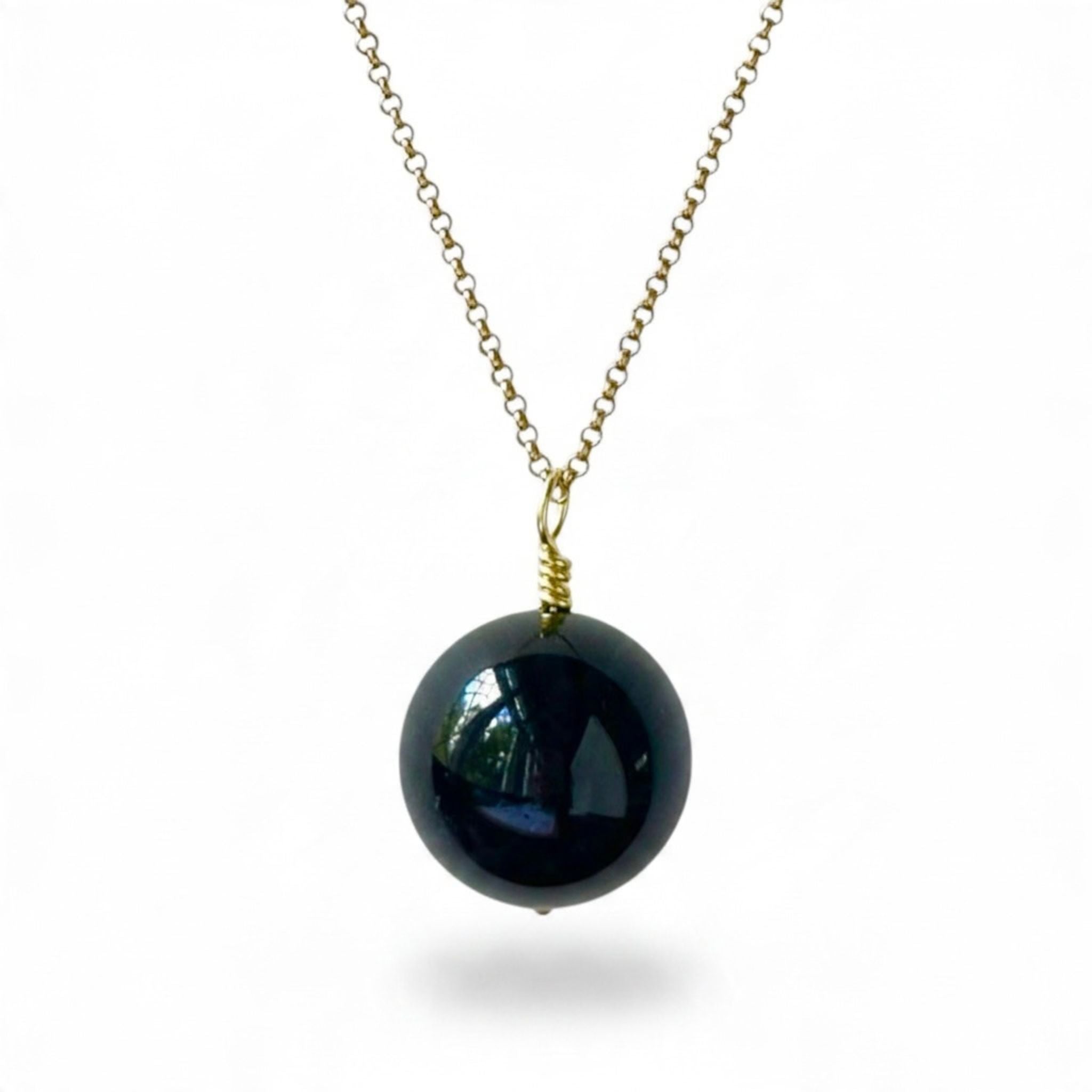 A gold chain necklace featuring a large, glossy black onyx pendant shown against a plain white background