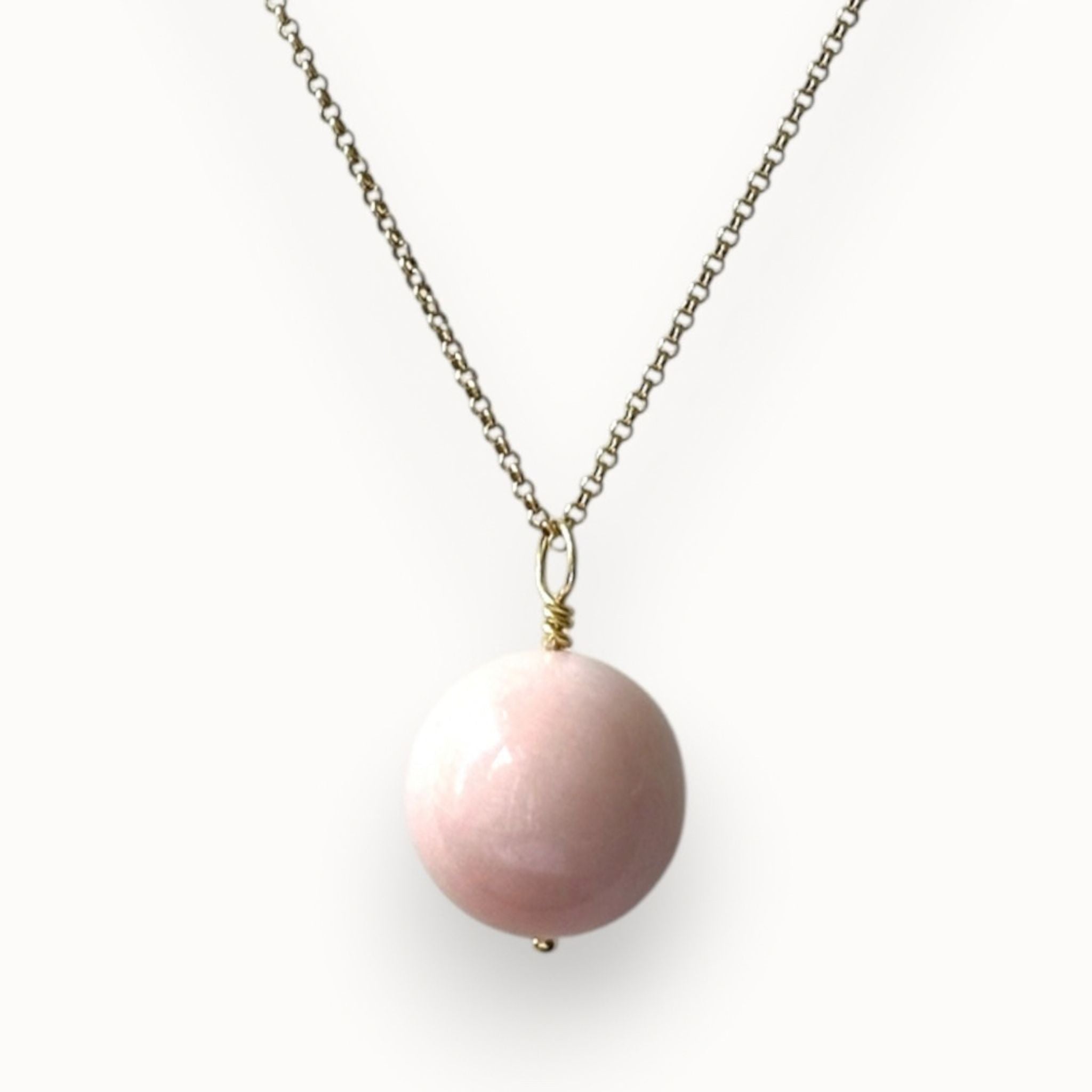 Pink agate pendant gold necklace on an off white background