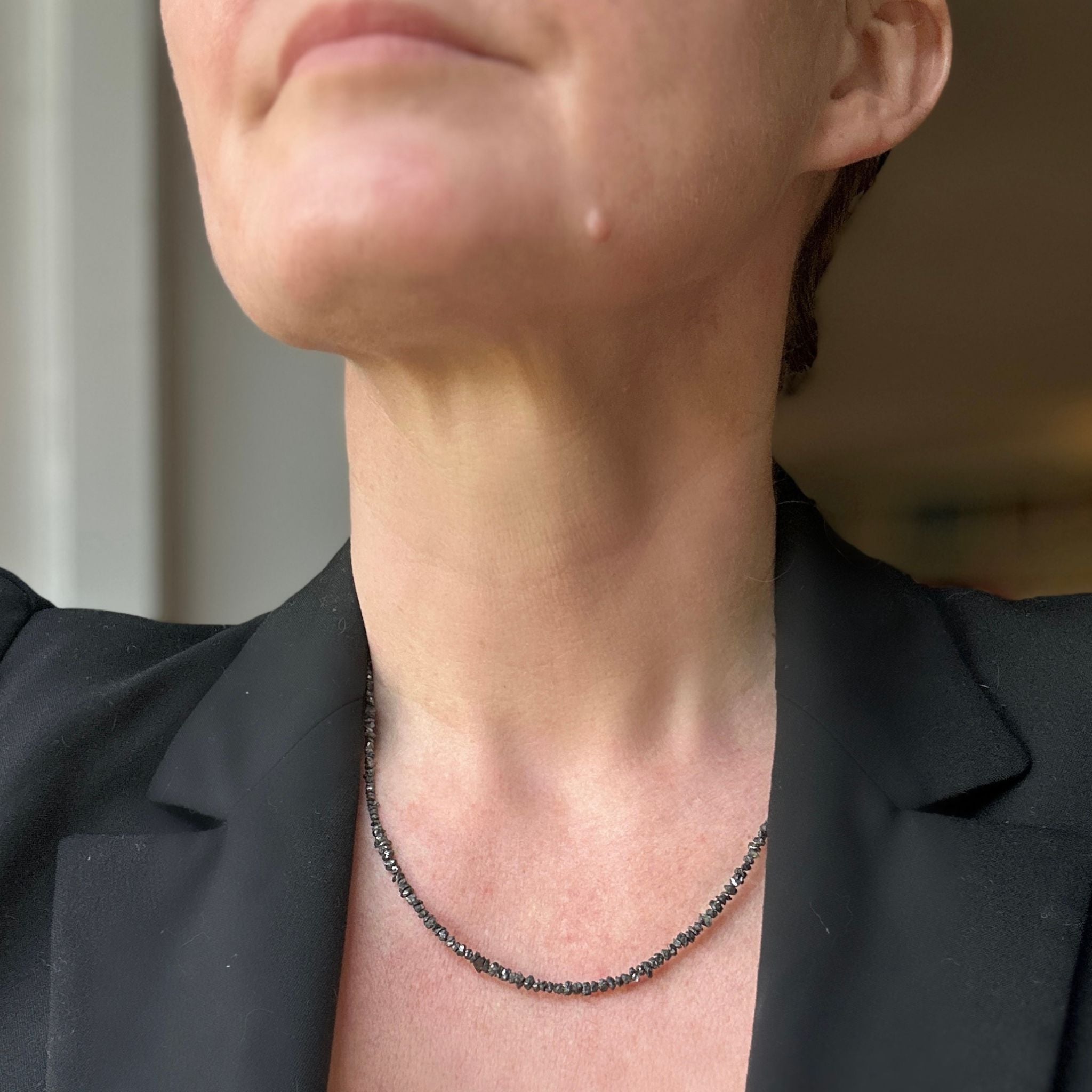Black raw diamond chip necklace in minimalist Scandinavian design modelled with black suit jacket