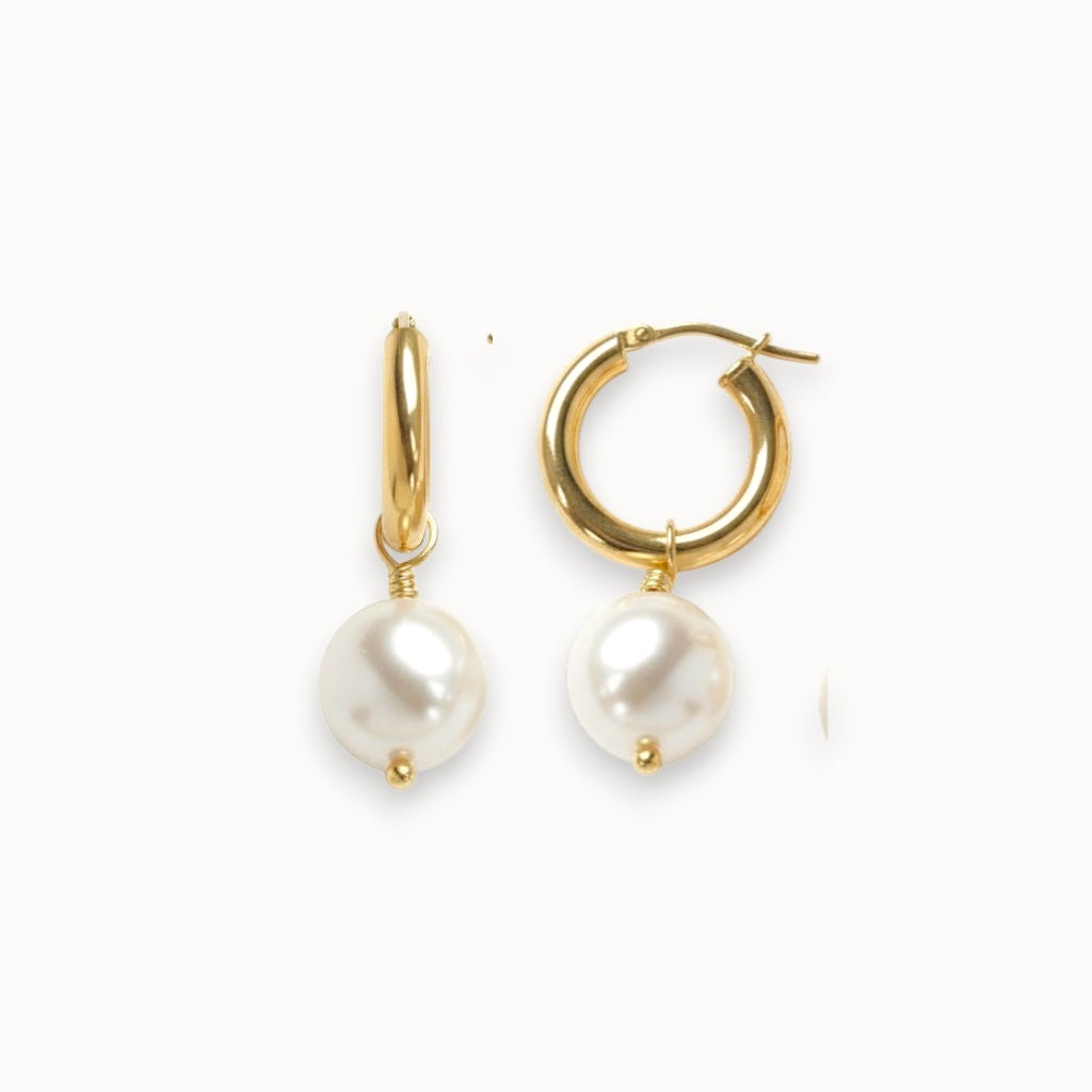 Gold hoop earrings with white pearls on a white background
