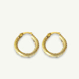 Delicate small gold hoops resting on a linen collared background