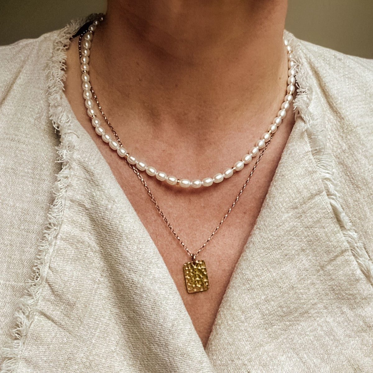 Elegant Pearl Necklace lying flat on a white background made with the highest quality freshwater pearls and 24K gold plated Sterling silver beads layered here for a more personal and laid back look