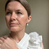 Woman wearing a white blouse with ruffled sleeves against a plain background
