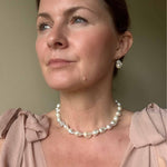 Baroque pearl necklace and earrings modelled against a dusty pink wedding guest dress
