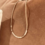 Gold wrap bracelet with pearls that doubles as a necklace on a rust velvet background 