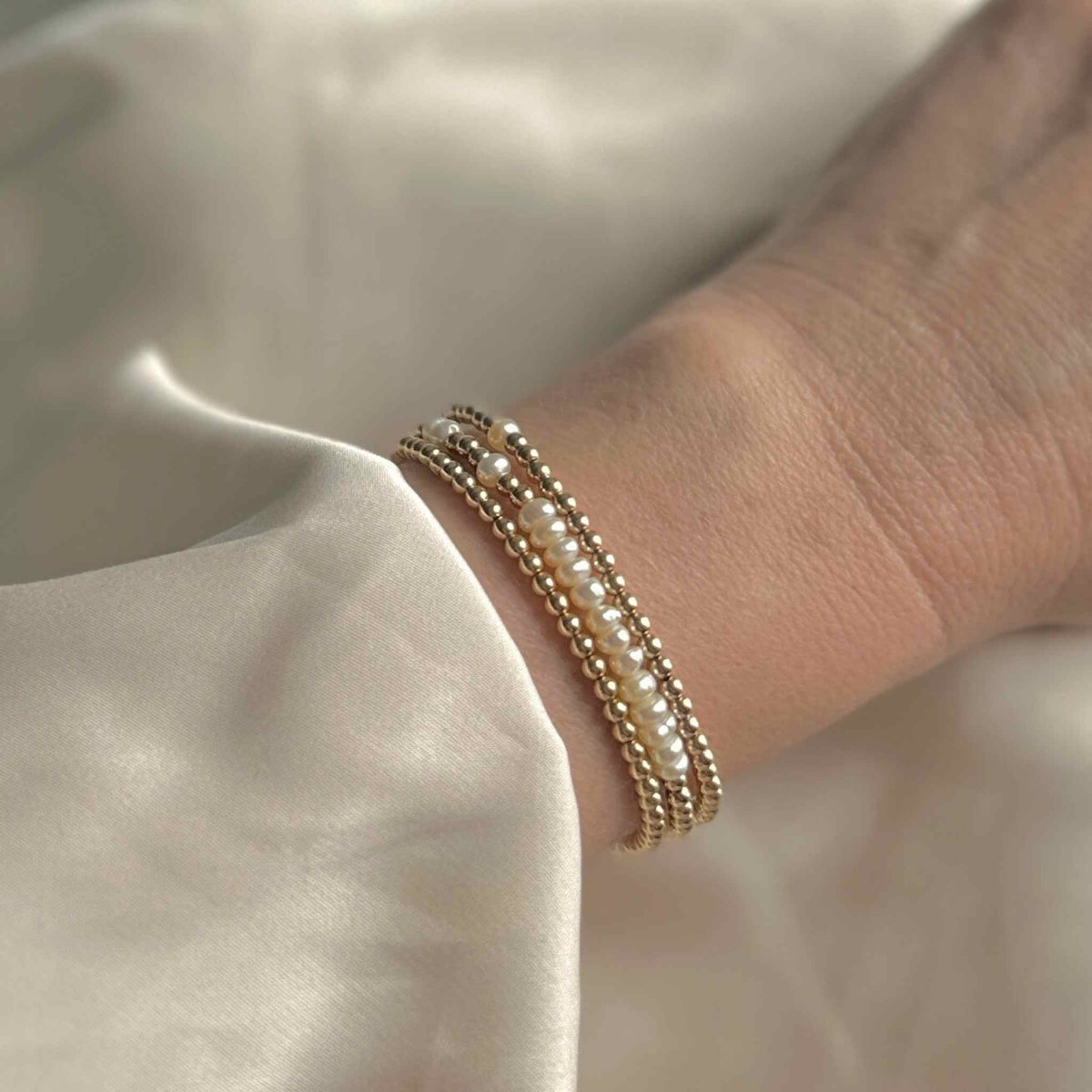 gold wrap bracelet with pearls worn with a cream silk wedding dress