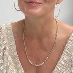 Woman wearing a gold-filled and pearl necklace with a plain background