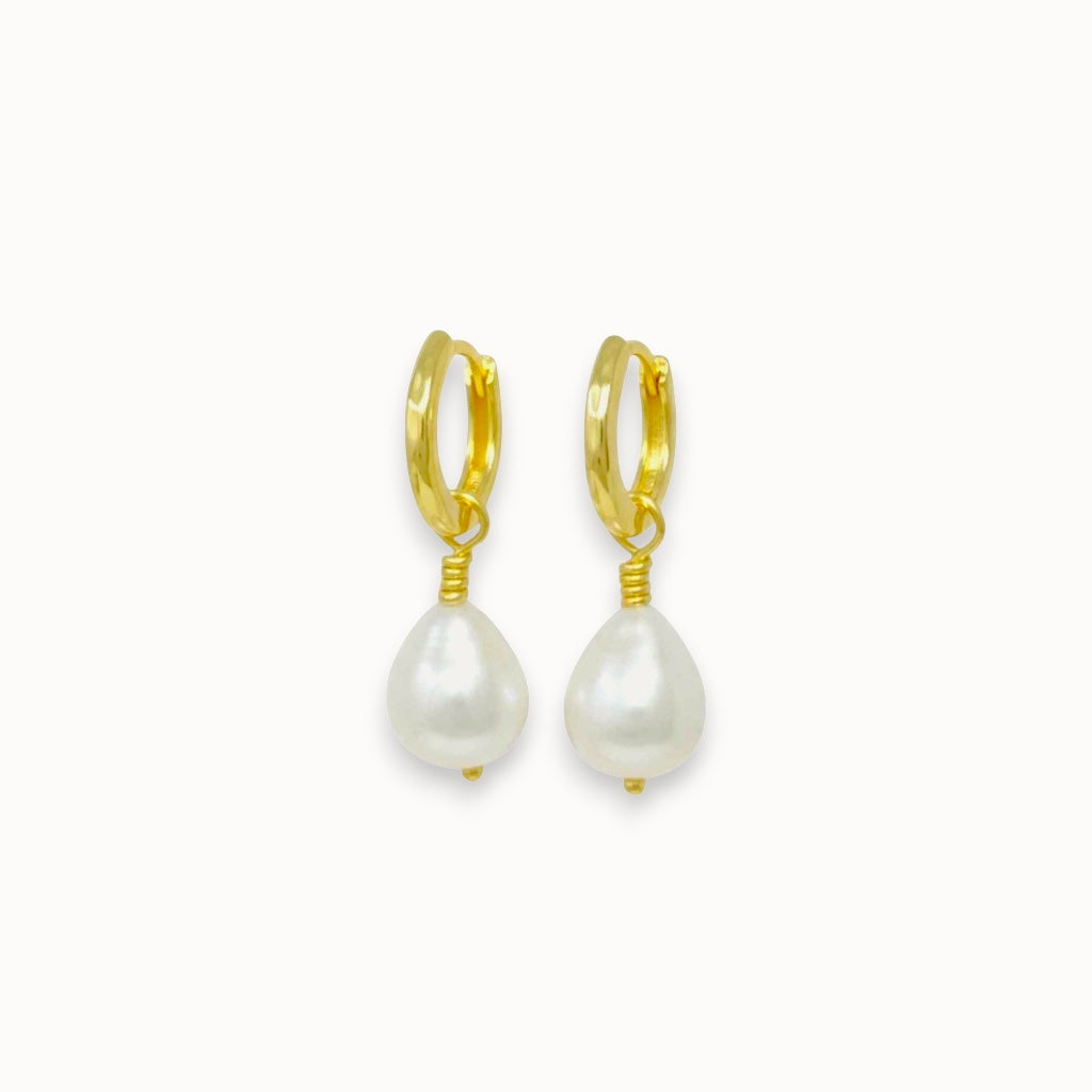 Gold hoop earrings with pearl drops on a white background
