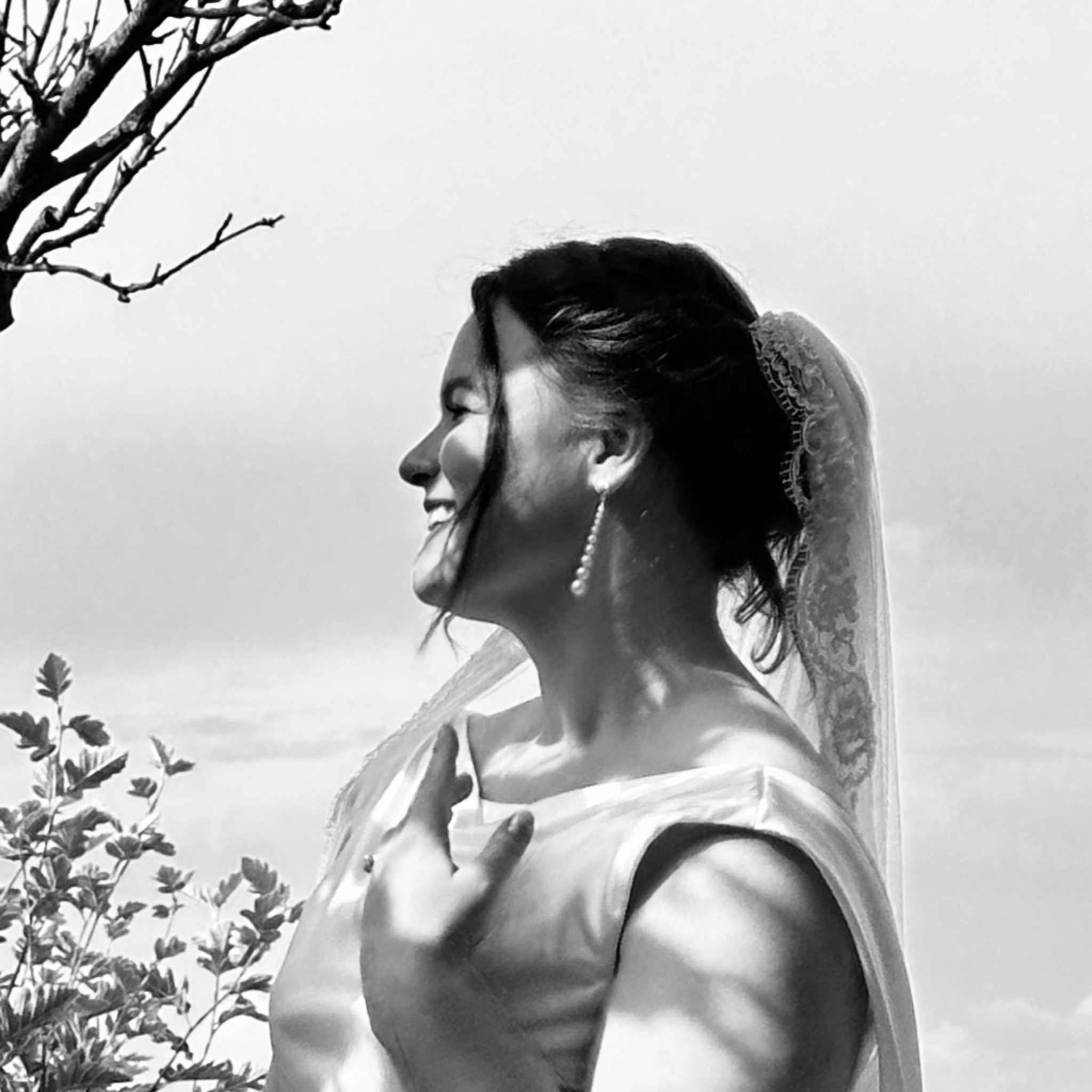 Black and white photo of a bride  with RAW earrings and a veil outdoors