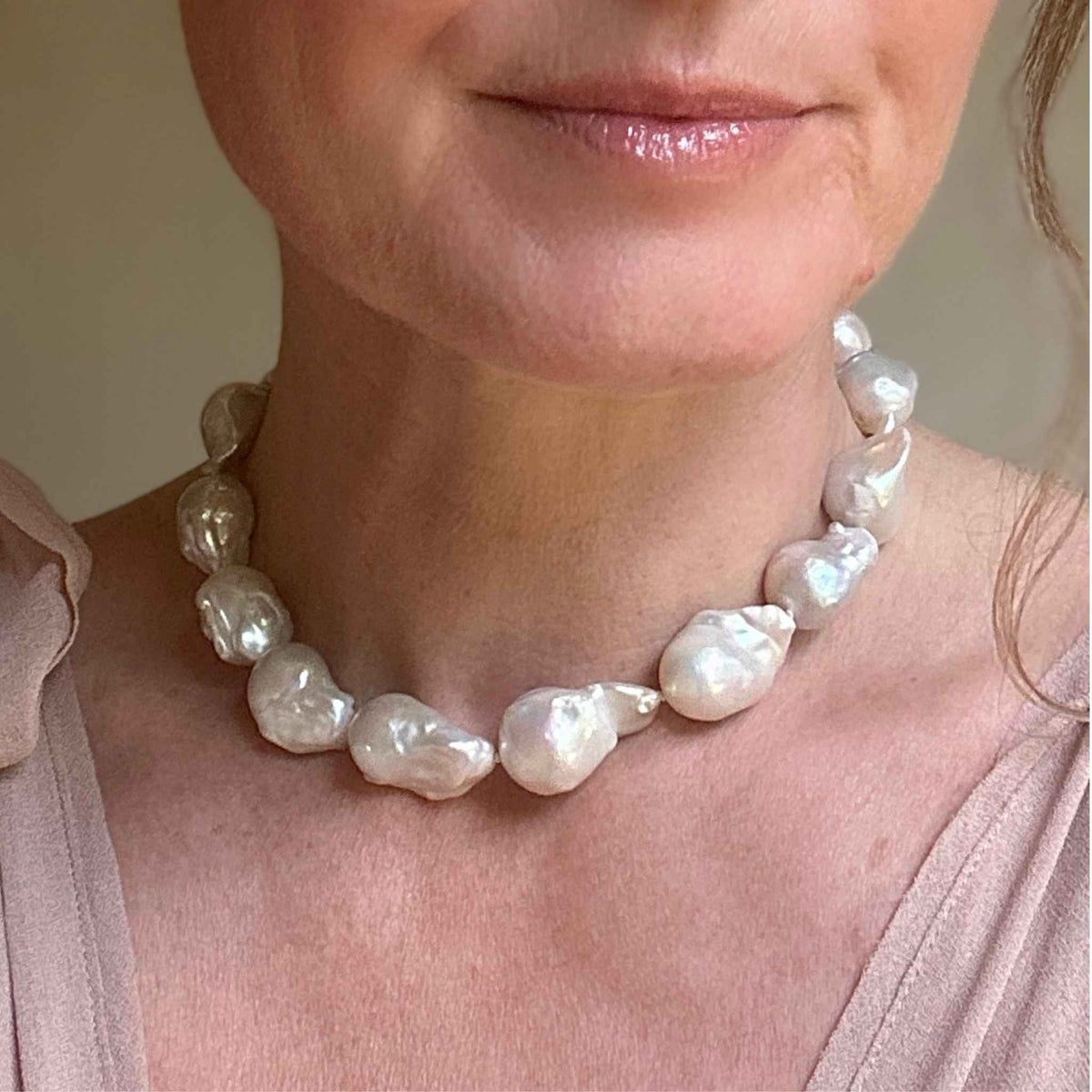 Large baroque pearl choker necklace modelled against a soft pink dress