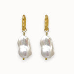 Pair of big white baroque pearl earrings with gold textured huggies
 on a white background