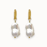 Pair of big white baroque pearl earrings with gold textured huggies
 on a white background