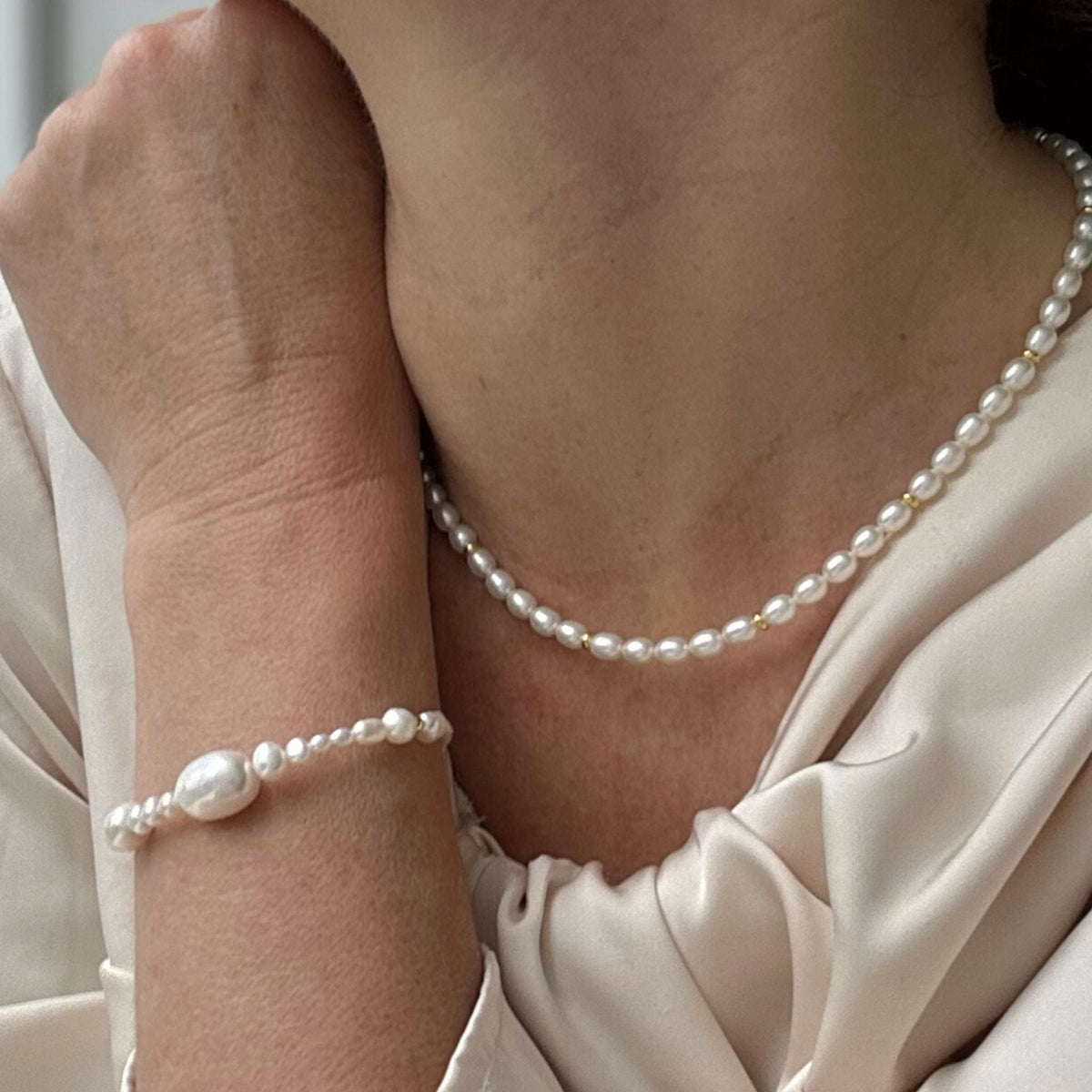 Elegant Pearl Necklace lying flat on a white background made with the highest quality freshwater pearls and 24K gold plated Sterling silver beads modelled here with understated chic long sleeve wedding dress