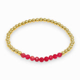 Gold beaded bracelet with pink beads on a white background