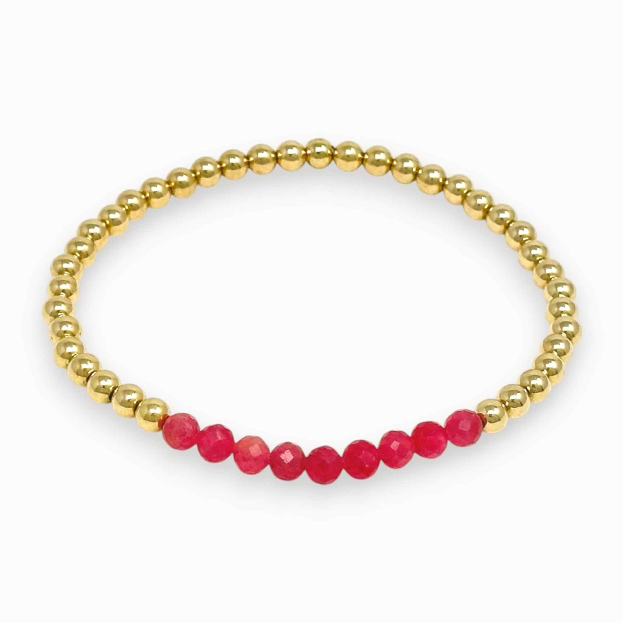 Gold beaded bracelet with pink beads on a white background