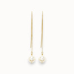Pair of pearl earrings with gold chains on a white background