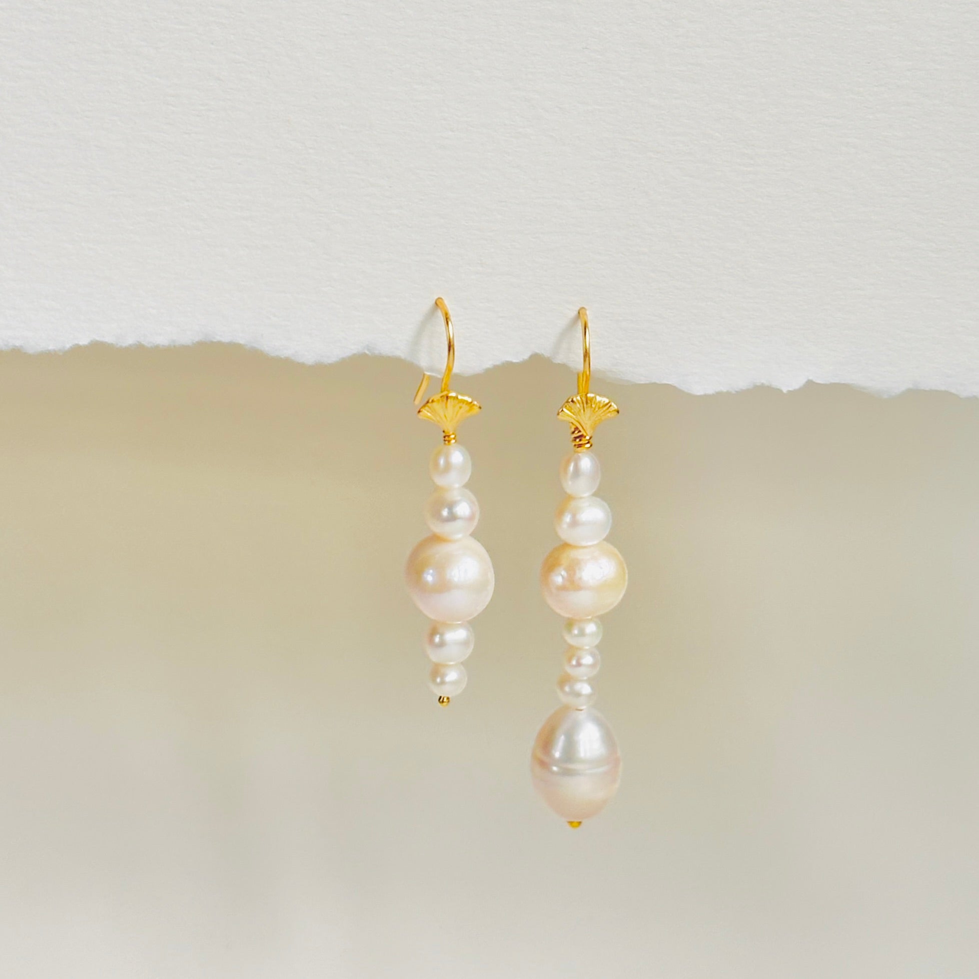 Stunning Scandinavian earring design with mismatched pearl drop on gold ear wire