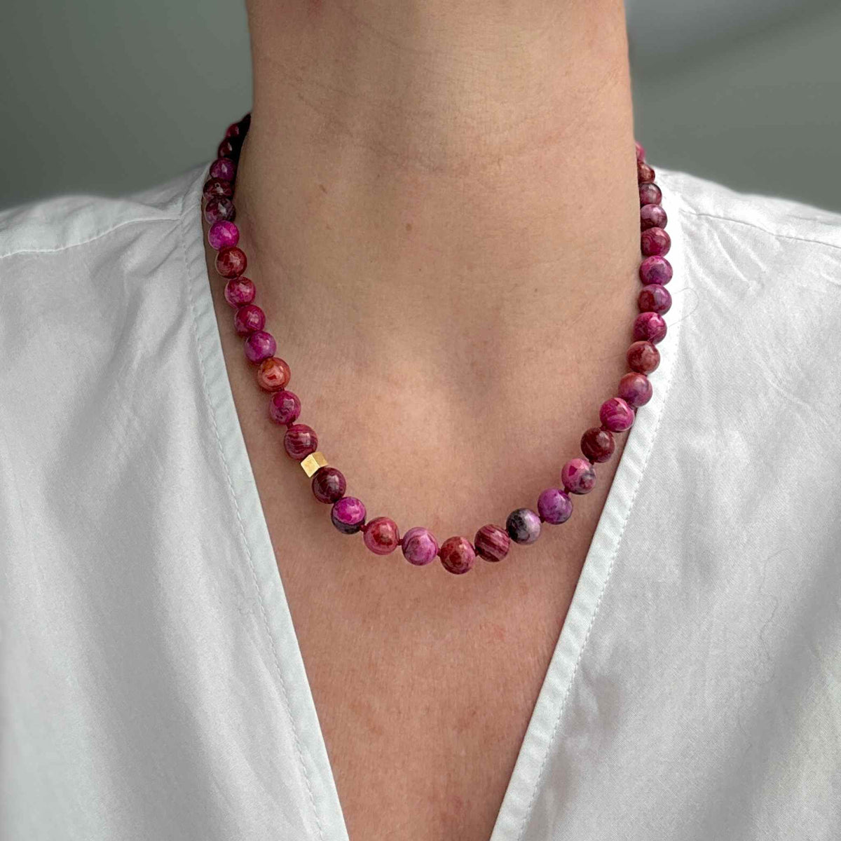 Pink agate necklace beaded modelled against white shirt