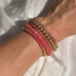 Stack of pink gemstone and gold beaded bracelets