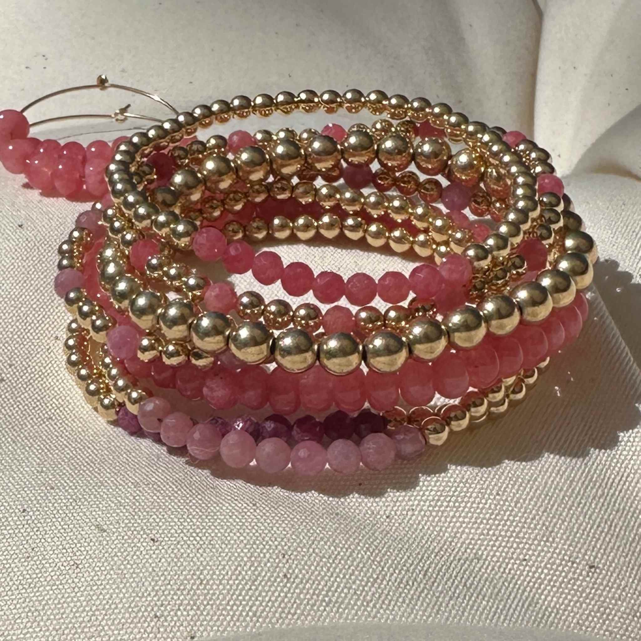 Stack of pretty pink gemstone and gold bracelets