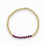 Gold bracelet with purple beads on a white background