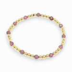 Bracelet with pink ruby beads and gold accents on a white background