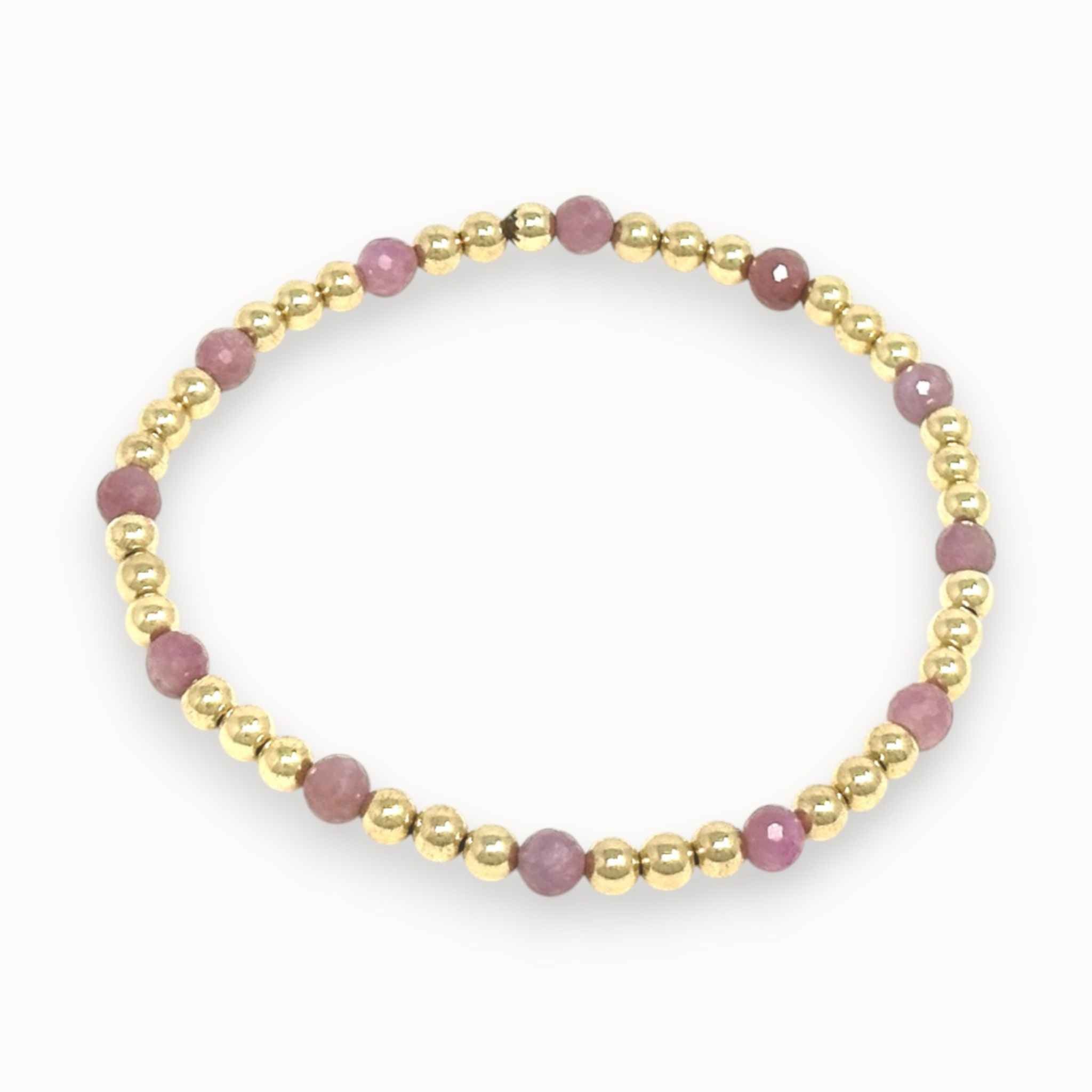 Bracelet with pink ruby beads and gold accents on a white background