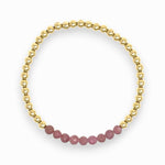 Gold bracelet with pink ruby beads on a white background