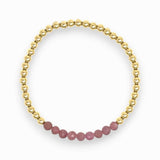 Gold bracelet with pink ruby beads on a white background
