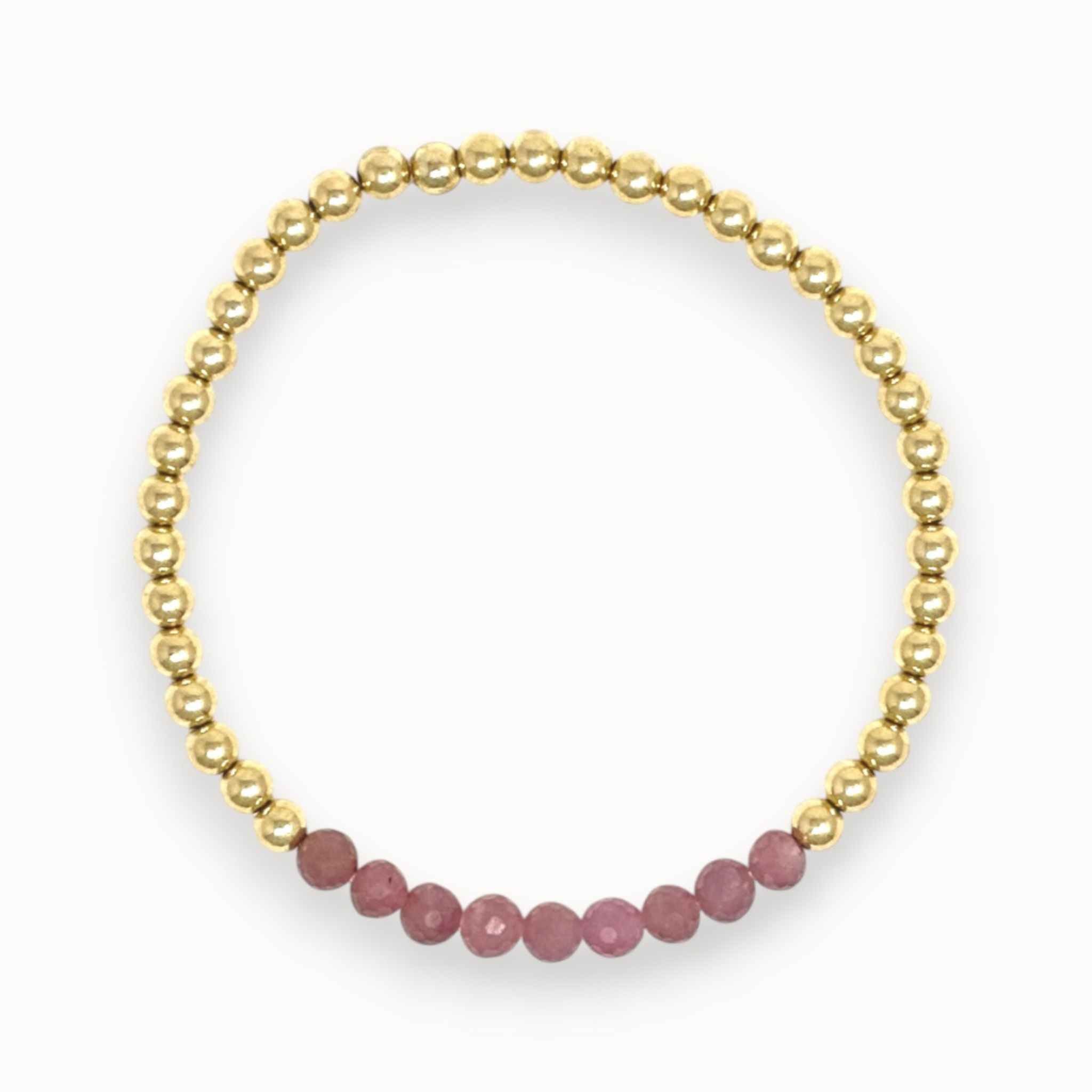 Gold bracelet with pink ruby beads on a white background