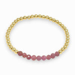Pink ruby and gold beaded bracelet on white background