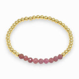 Pink ruby and gold beaded bracelet on white background