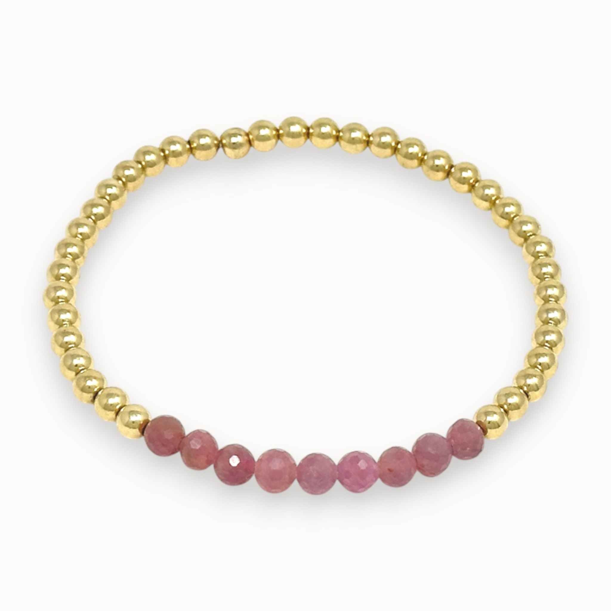 Pink ruby and gold beaded bracelet on white background
