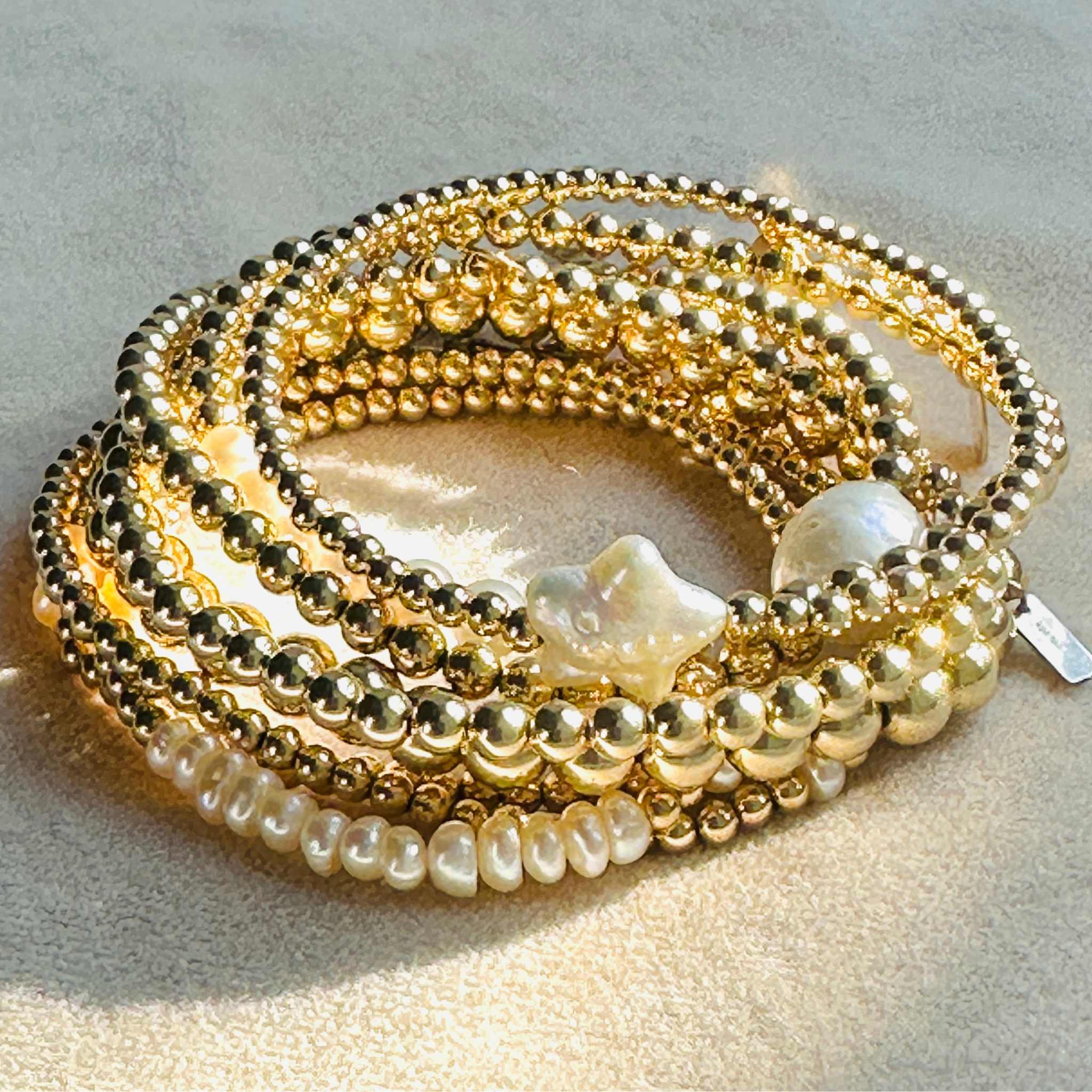 Stack of gold and pearl beaded bracelets on a light background
