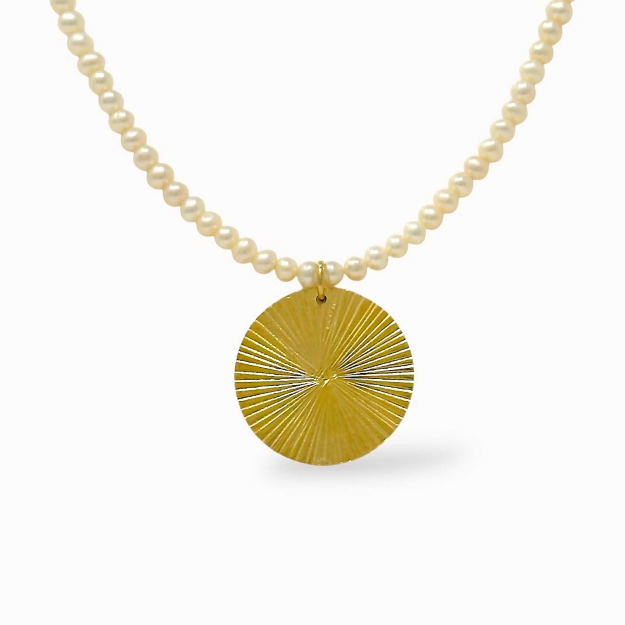Pearl necklace with a gold disc pendant on a white background