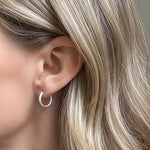 Close-up of a person wearing a silver hoop earring with soft lighting.