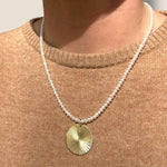 Gold Disc pendant on pearl necklace modelled against a beige cashmere jumper from Bella Freud