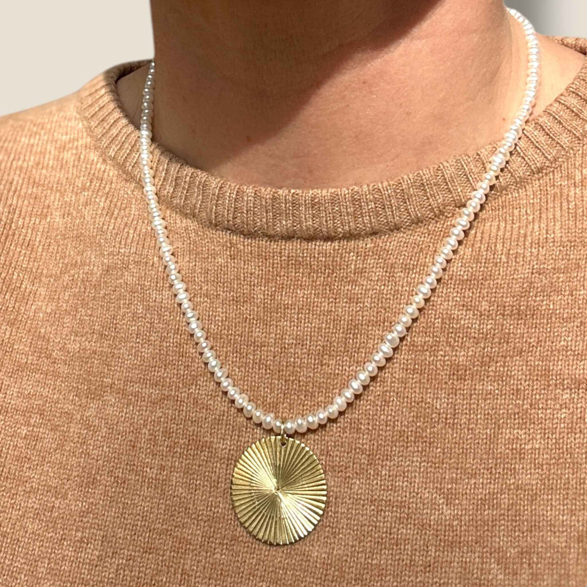 Gold Disc pendant on pearl necklace modelled against a beige cashmere jumper from Bella Freud