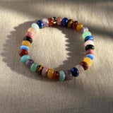  The RAW Charity Bracelet in Support of Amnesty International  with multicoloured gemstones on beige velvet background