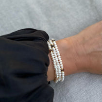 Triple wrap pearl bracelet and necklace in one with gemstone and gold vermeil accent, modelled with black ballon sleeved Ulla Johnson dress
