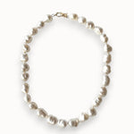 A strand of irregular white baroque pearls arranged in an oval shape, secured with a small gold clasp, shown on a clean white background.