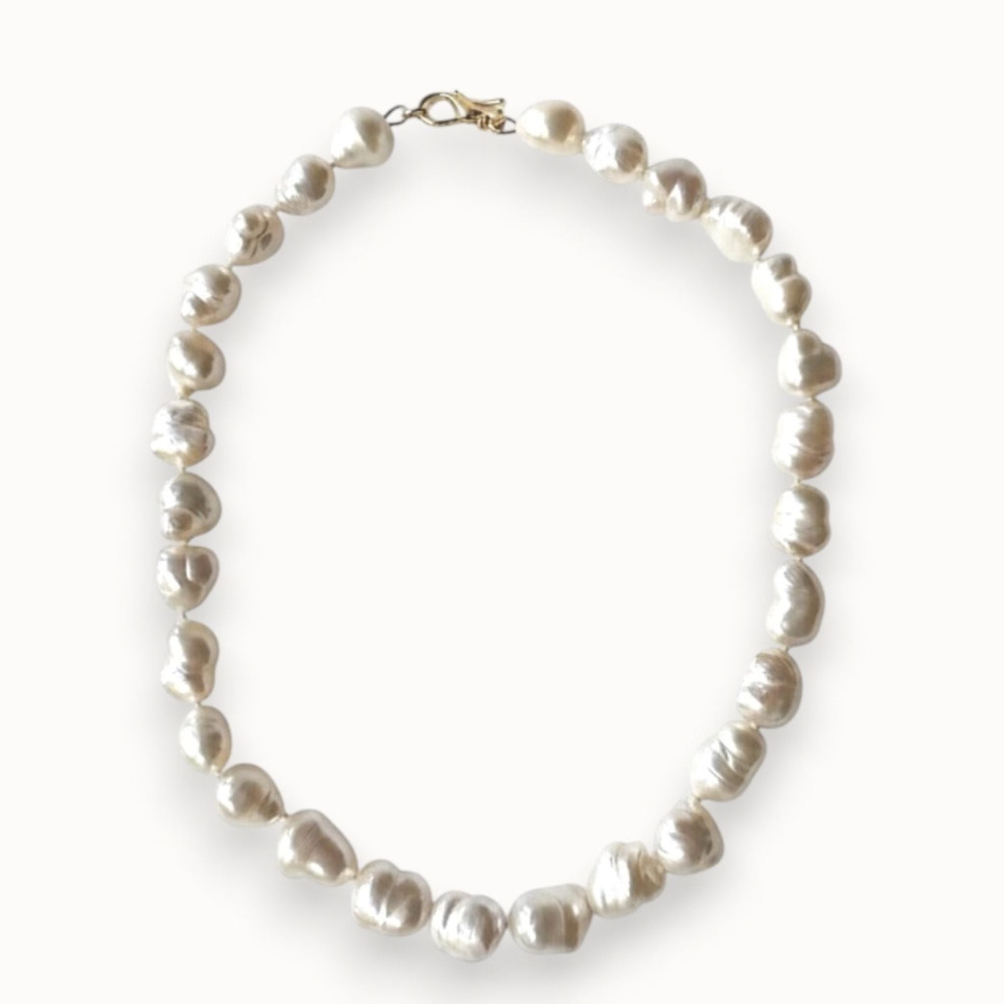 A strand of irregular white baroque pearls arranged in an oval shape, secured with a small gold clasp, shown on a clean white background.